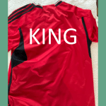 Red custom football jersey with a personalized name printed in bold white text on the back.
